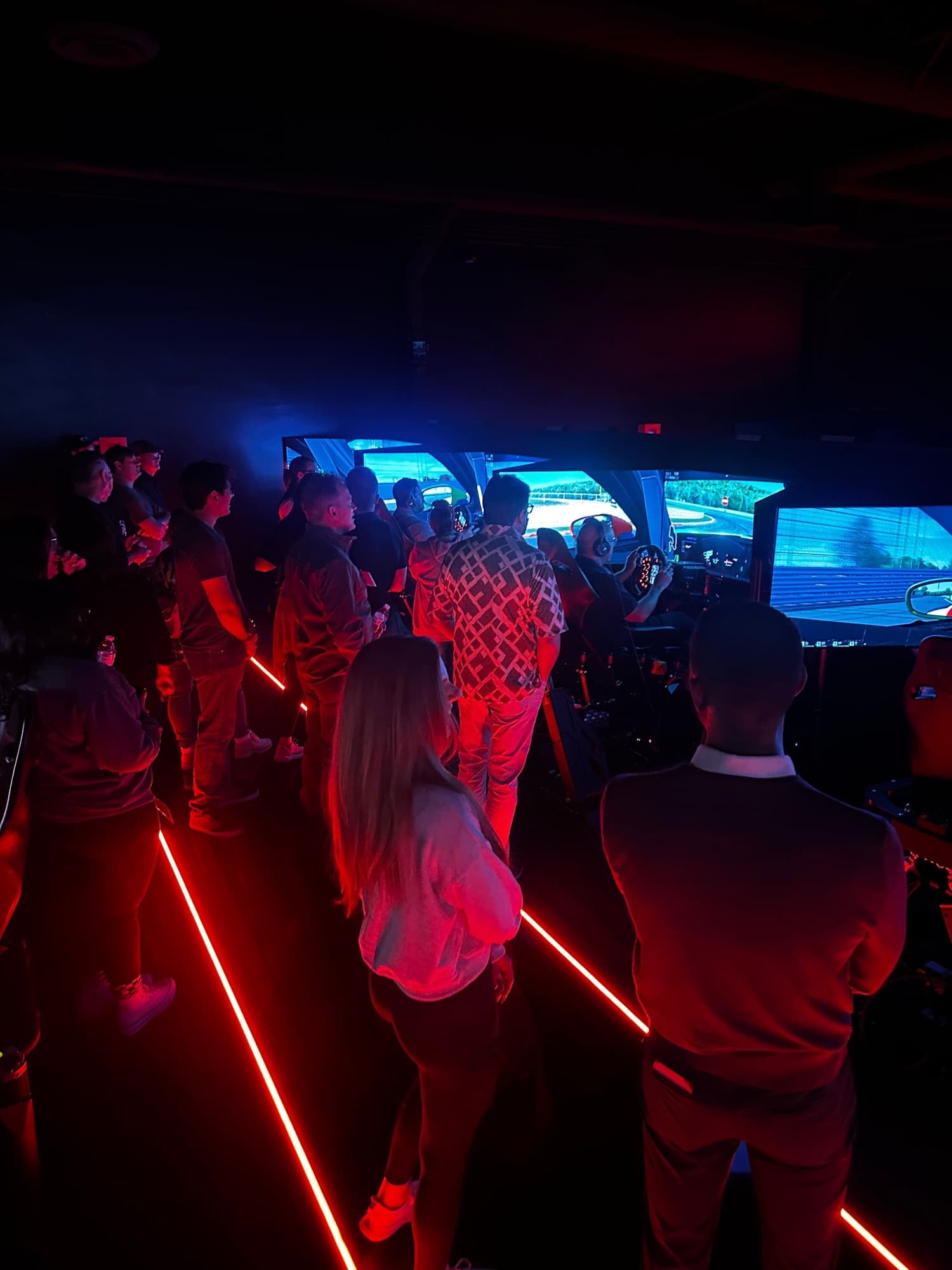A group of colleagues watching a teammate race on a row of World of Racing sims