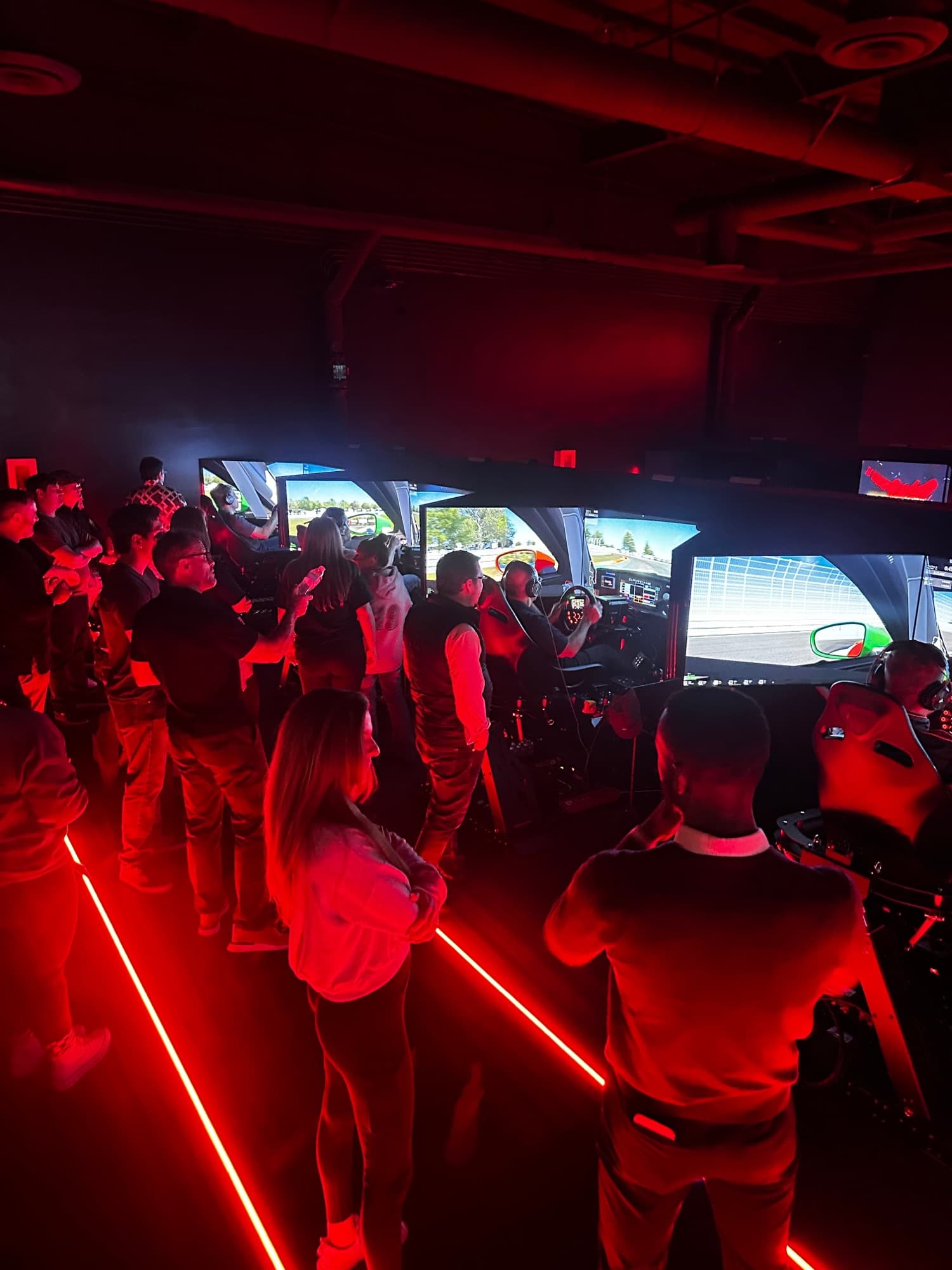 A group cheering on the drivers in the sim room at World of Racing