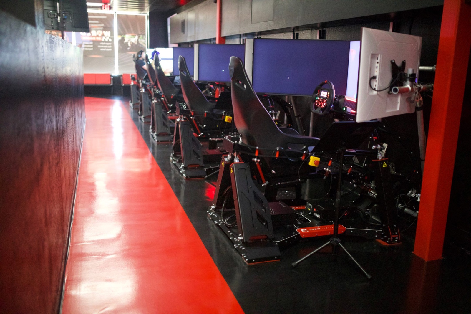 Row of full-motion World of Racing sim rigs with racing seats, force-feedback wheels, and screens